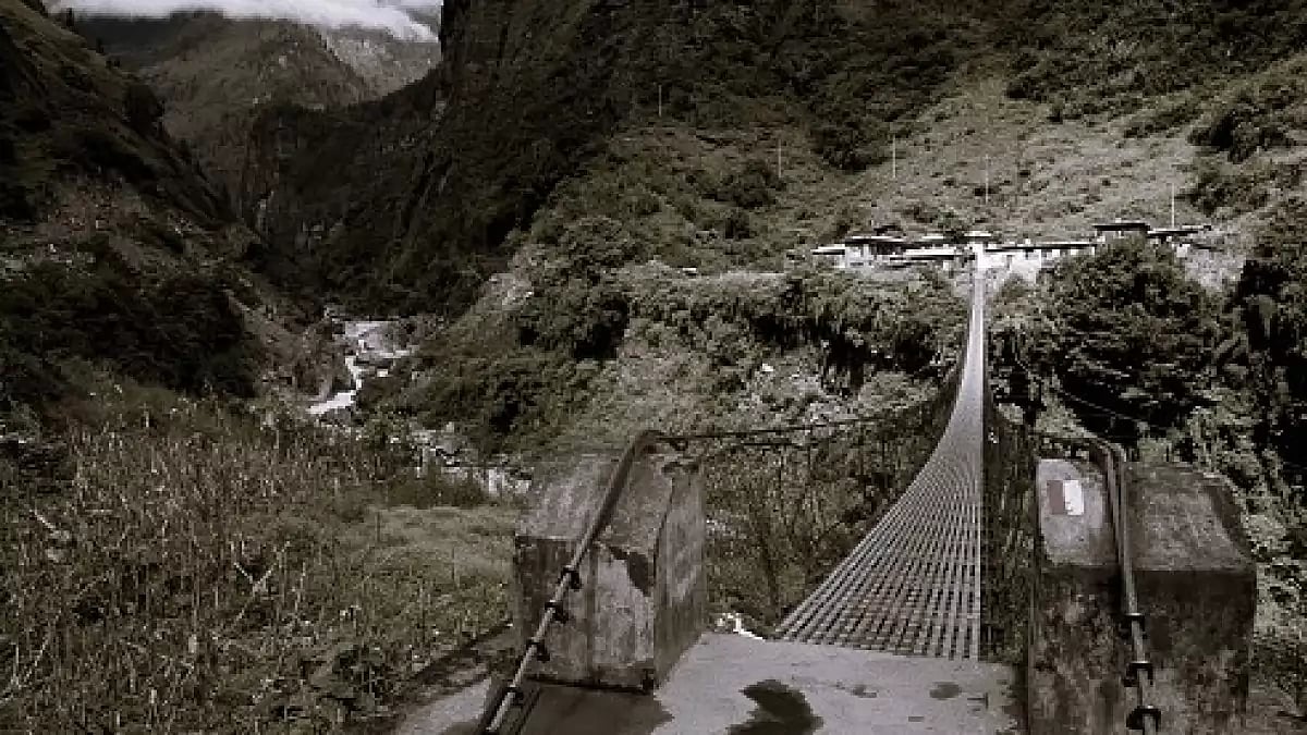 Long suspension foot bridge with silhouette of walking woman, bridge over deep valley in mountains