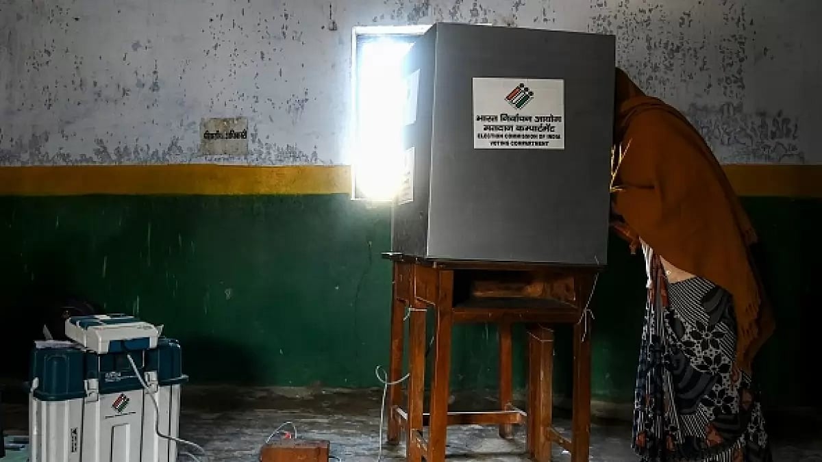 A voter casts her ballot at a polling station in Vrindavan on February 10, 2022 during the 1st Phase