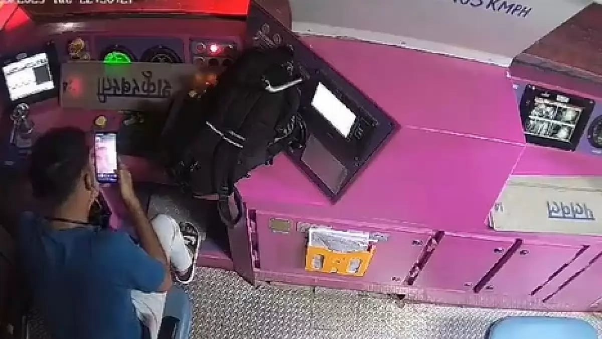 The railway staffer busy watching his mobile phone while putting his bag on the throttle 