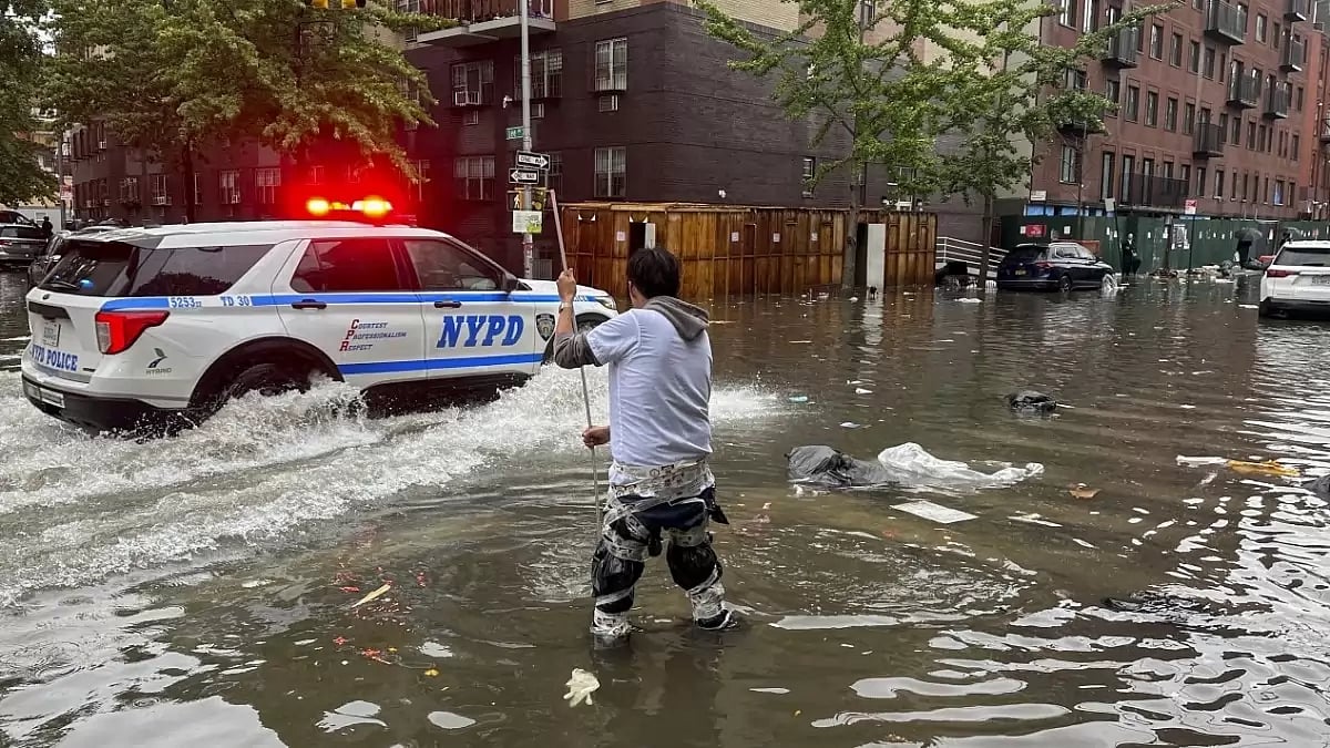 A man works to clear a drain in flood waters on Friday in the Brooklyn Borough of New York