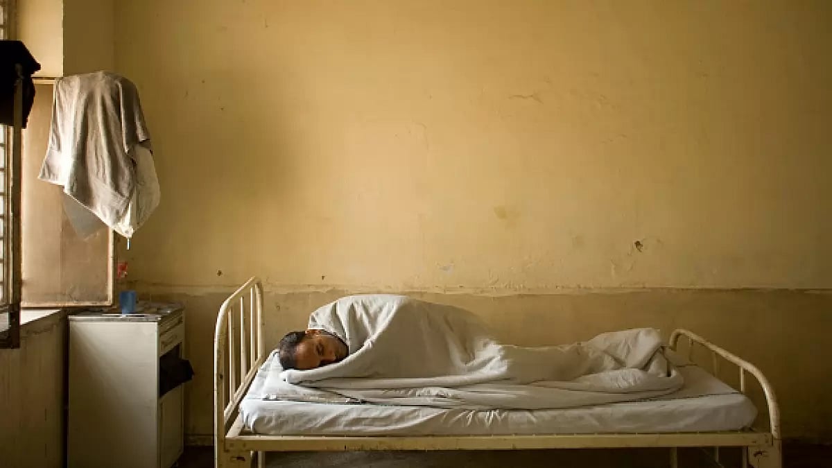 A mentally ill patient sleeps in his bed in a ward at the IHBAS, Delhi.