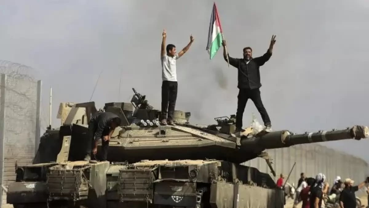 A Palestinian waving national flag standing on a destroyed Israeli tank