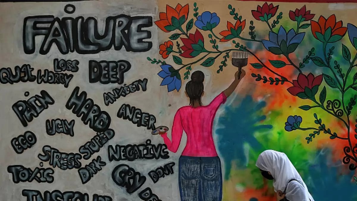 A college student walks past a graffiti on World Mental Health Day in Srinagar.