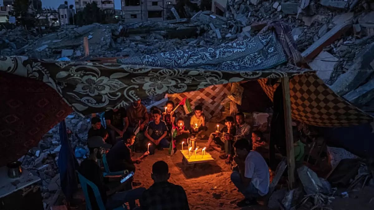 Palestinian children hold candles during a rally amid the ruins of houses destroyed by Israeli strikes in Gaza Strip.
