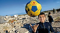 A Palestinian boy plays amidst the rubble of the destroyed Al-Aqsa university