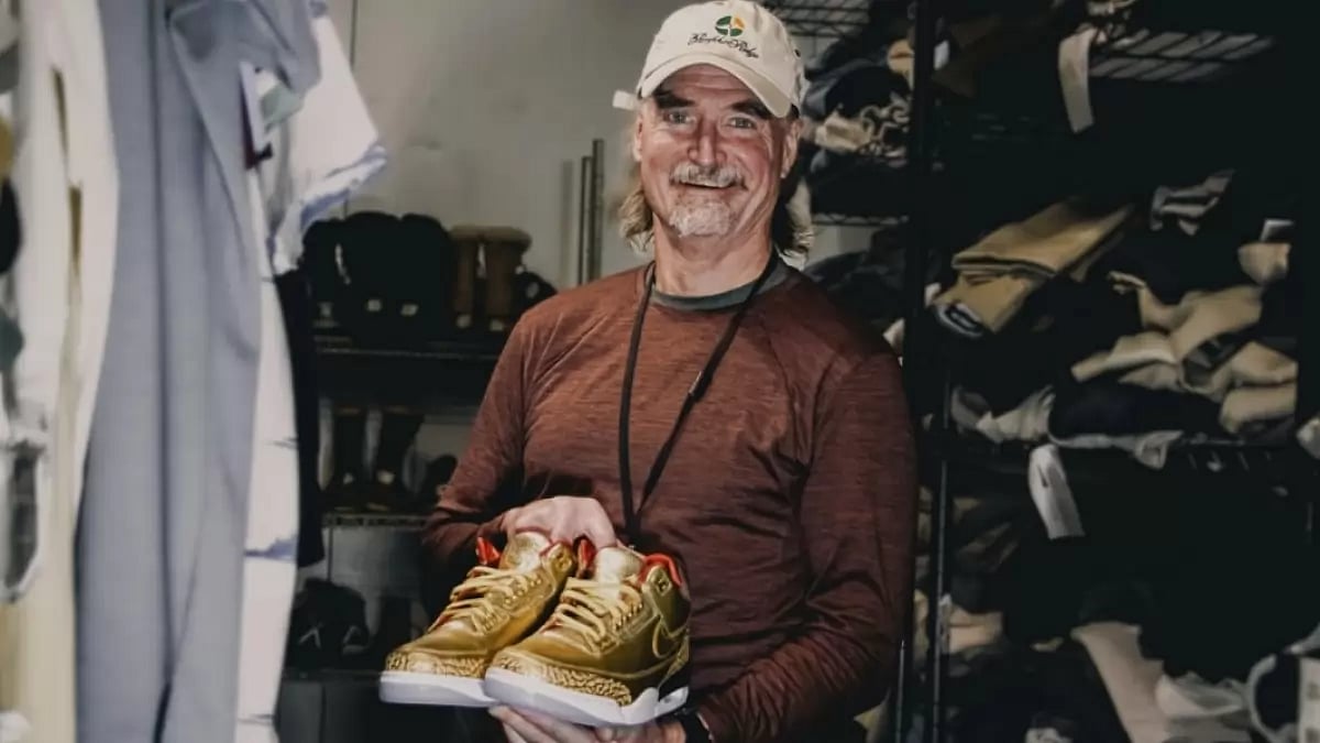 James Free posing for a photo with a pair of gold Nike Air Jordan 3 sneakers. 