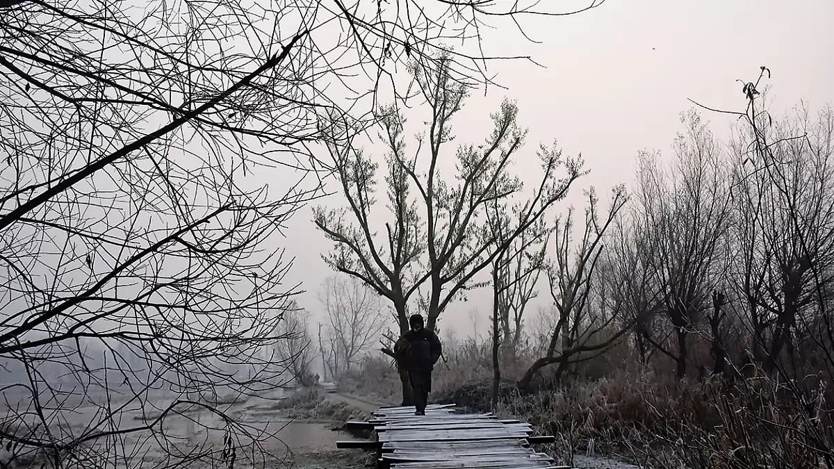 Winter in the Valley: A man crosses a footbridge at the floating vegetable market of Dal Lake, Srinagar on a wintry morning - null