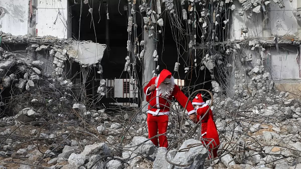 A Palestinian dressed as Santa Claus with his child walk past the al-Jawhara Tower in Gaza City.