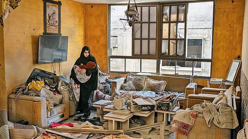 A Palestinian woman holds her child after an Israeli strike on her neighbourhood in Gaza Strip