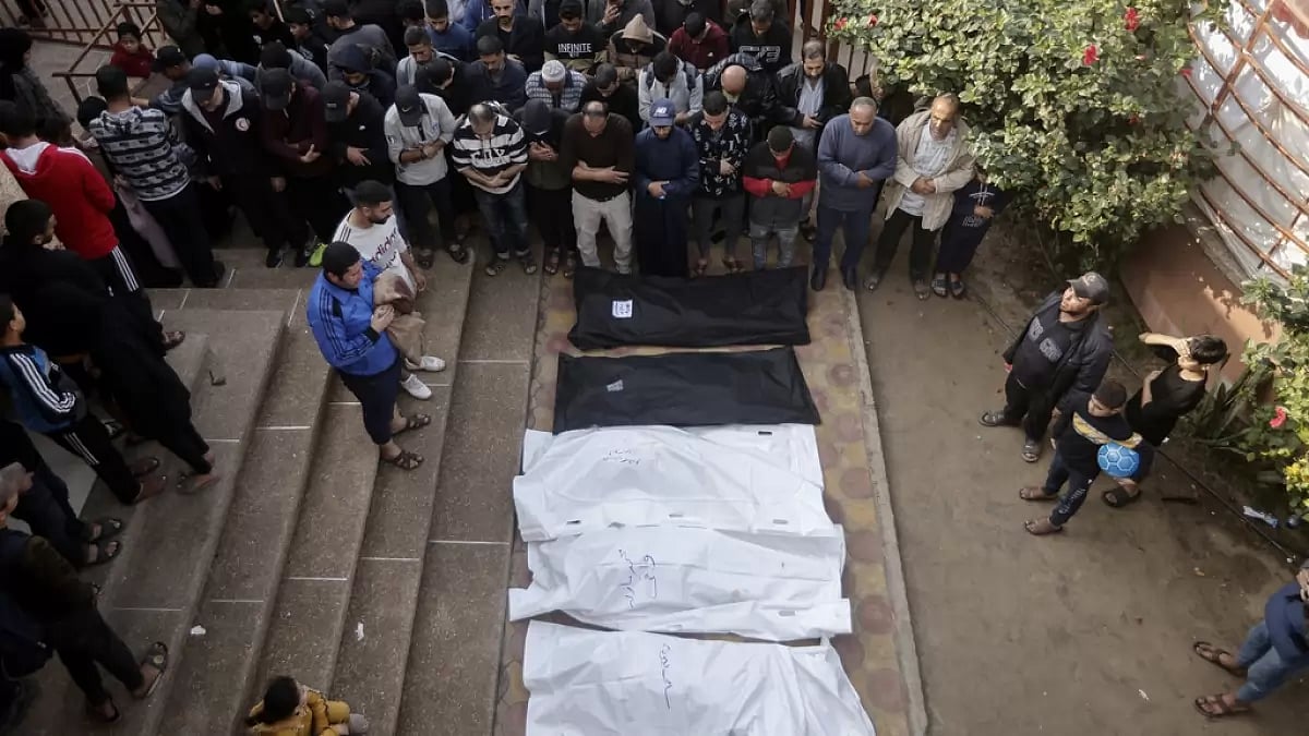 Palestinians pray near the wrapped bodies of relatives killed in the Israeli bombardment of Gaza