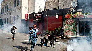 A Palestinian journalist carries away a child as other photojournalists assist a falling woman