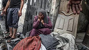 An injured woman cries near a lifeless body after Israeli airstrikes hit Ridwan area in Gaza City.