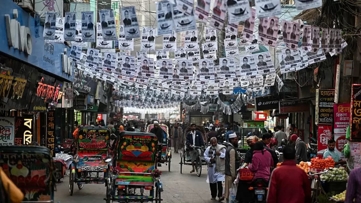 People walk along a street decorated with election posters ahead of the 7 January national elections