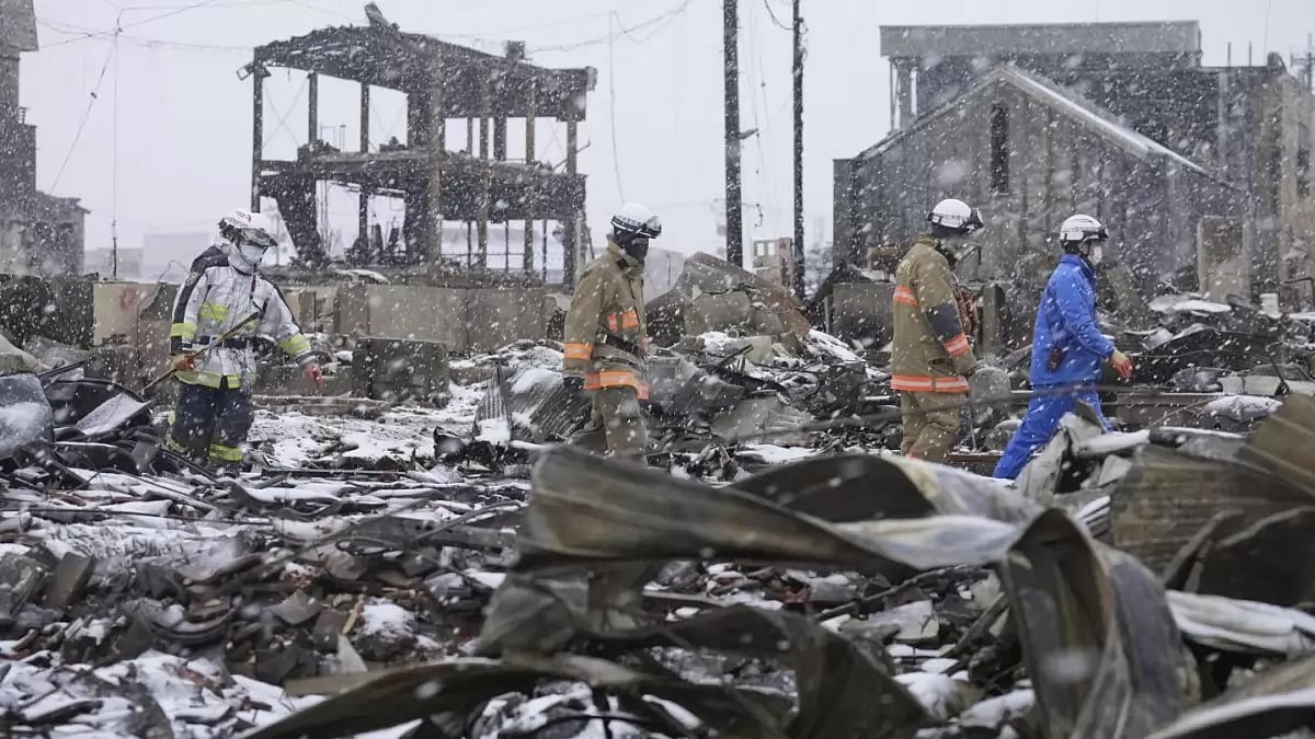 Rescuers searching through rubble in Japan's Wajima amid snowfall.