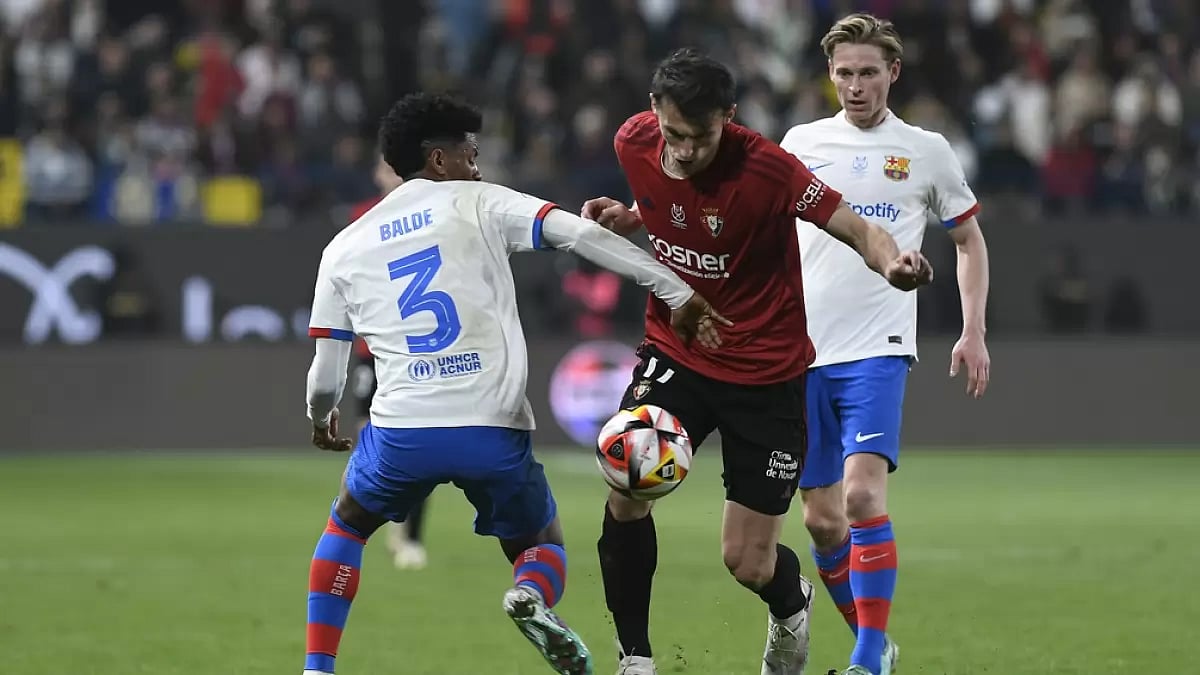 Alejandro Balde, left, fights for the ball with Ante Budimir, centre, during the Spanish Super Cup semi-final football match between Osasuna and Barcelona at Al Awal Park Stadium in Riyadh.