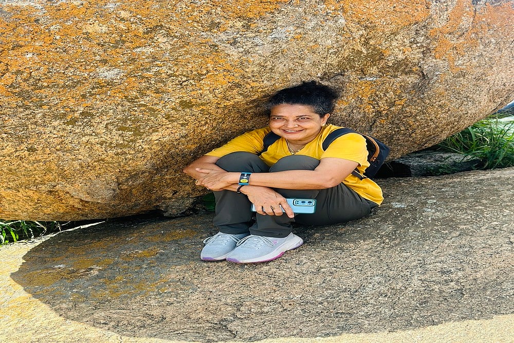 Yasmin with a backpack sitting under a rock