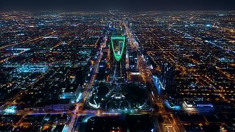 Aerial view of Riyadh at night, with the illuminated Kingdom Tower in the center