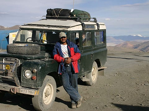 Neil Law poses with a land rover against the Himalayas 