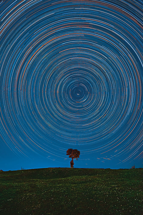 A three-hour-long star trail shot showing the earth's motion around its axis. The streaks at the bottom are the flaring up of satellites that crossed the frame