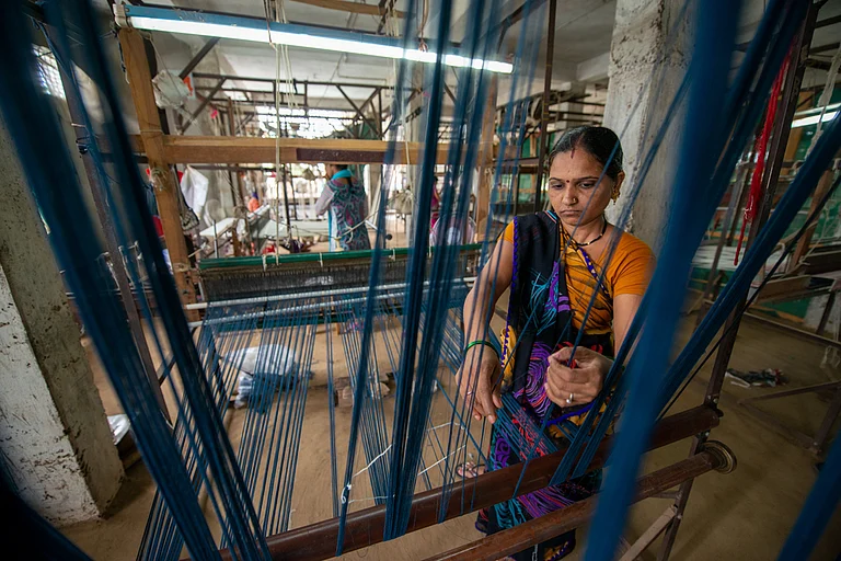 A woman weaver prepares threads for a Maheshwari saree on a loom - Pradeep Gaurs / Shutterstock