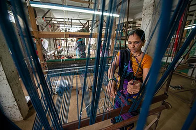 Pradeep Gaurs / Shutterstock : A woman weaver prepares threads for a Maheshwari saree on a loom