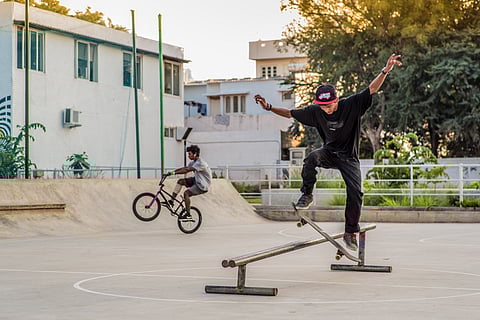 A boy skateboards as another rides a BMX