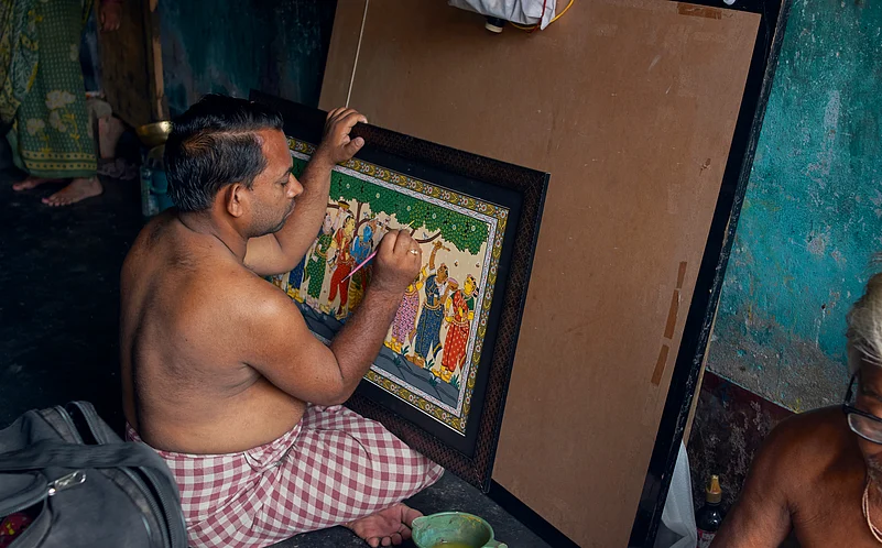 A rural artisan painting on a minutely detailed framed Pattachitra art