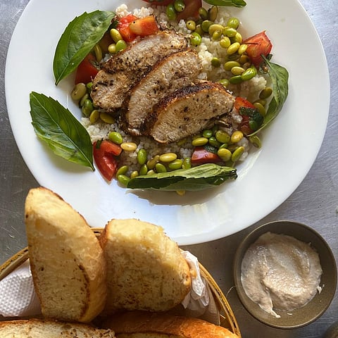 A take on couscous salad but with corn grits, edamame, pan seared chicken breast, tomatoes, basil & mint, with a side of tahini & fresh bread 