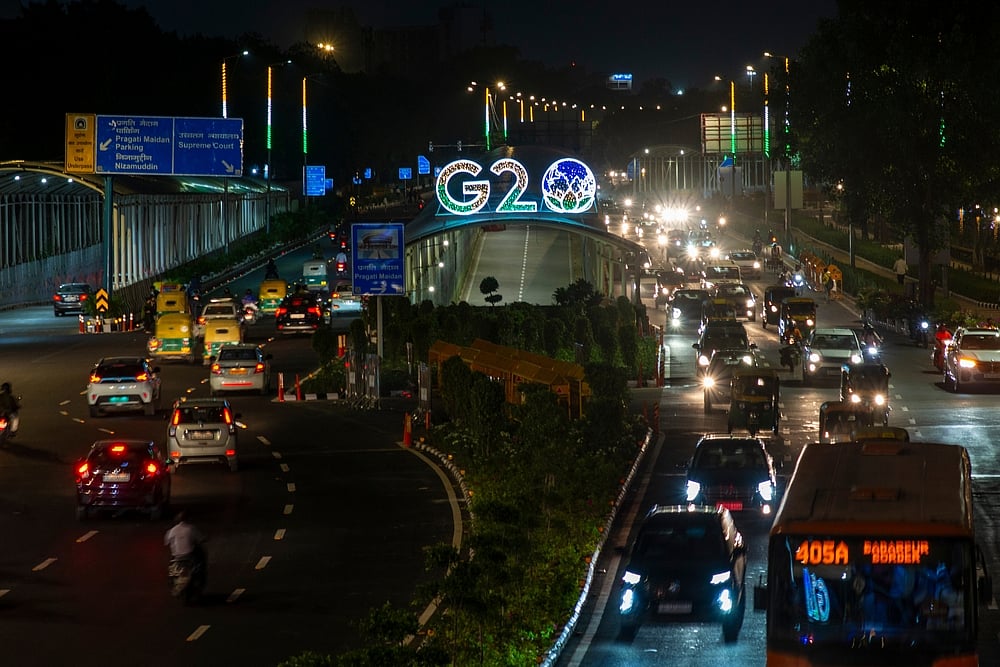 Pradeep Gaurs / Shutterstock : Traffic moves past a G20 logo installed on road outside the main venue of the upcoming G20 Summit