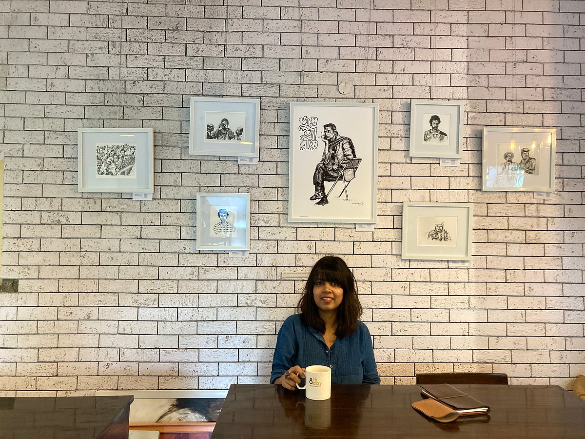 Roy with framed artworks at 8th Day Cafe