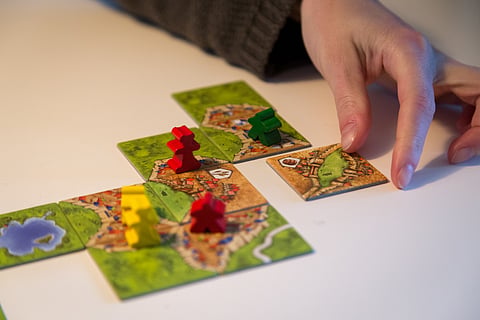 Carcassonne and a hand adding a tile