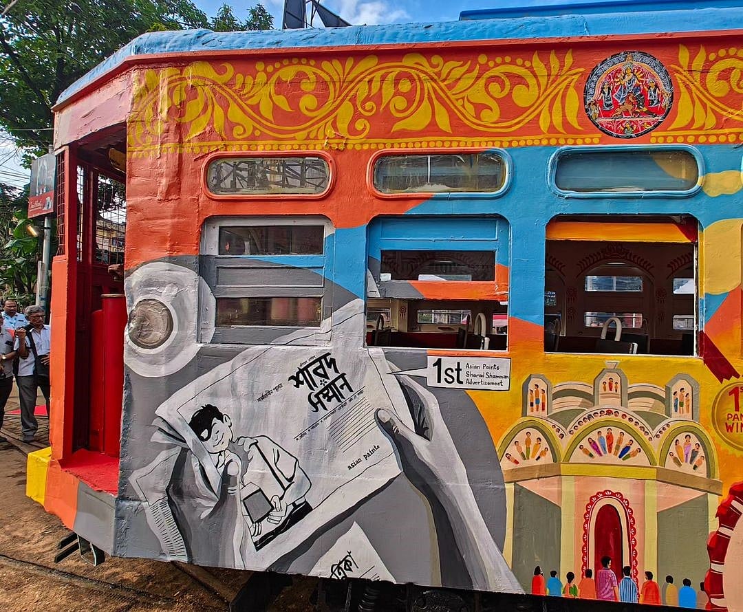 The artwork includes various elements of the pujas and life in the city