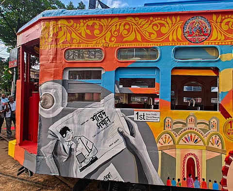 The artwork includes various elements of the pujas and life in the city