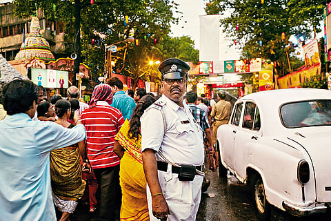 Crowd Control: People walking towards a pandal as a cop looks on