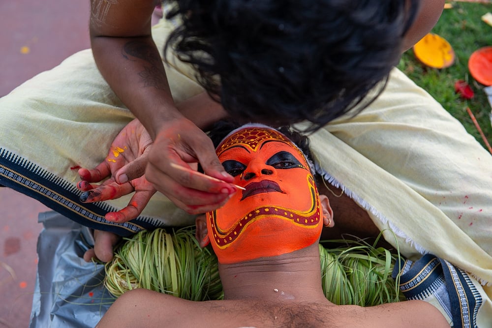 A theyyam artist gets his face painted