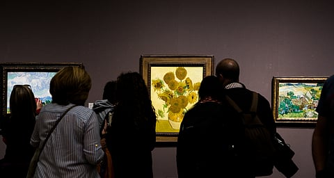 Onlookers examining "Sunflowers" by Vincent van Gogh
