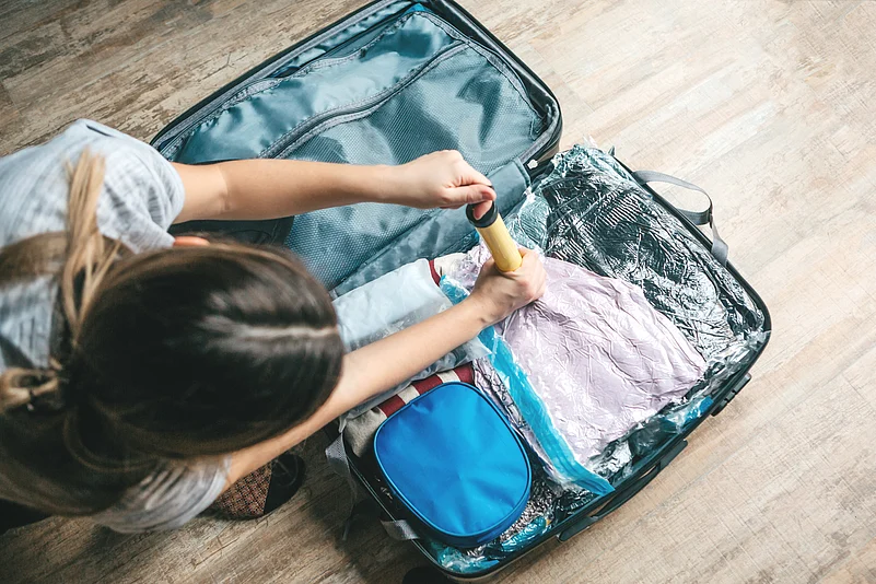 A girl packs things or clothes with a vacuum pump to save space in a travel suitcase
