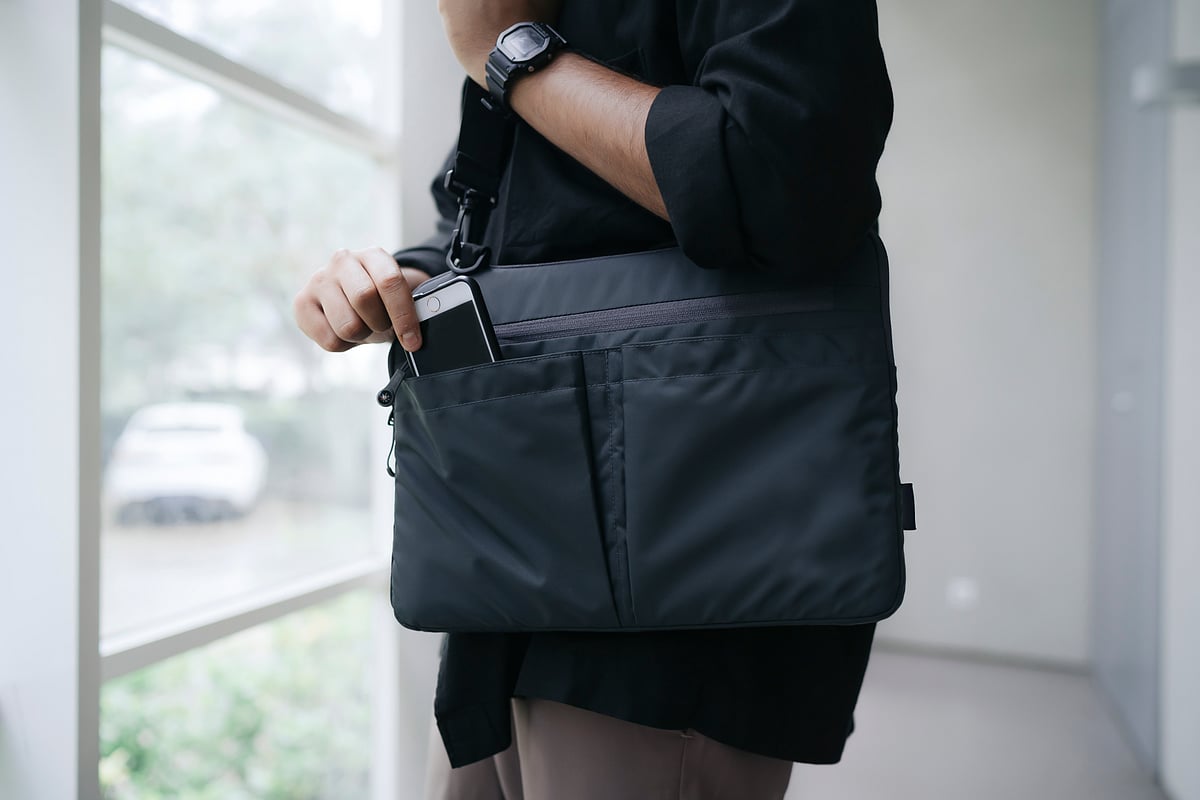 A man keeping his phone inside a laptop bag