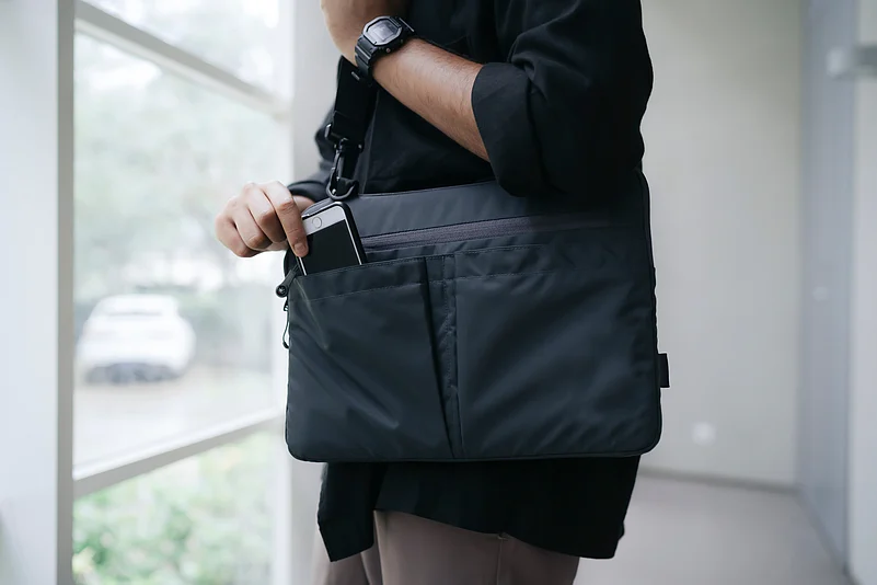 A man keeping his phone inside a laptop bag