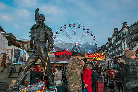 Freddie Mercury statue on waterfront of Geneva Lake and Christmas market in the background, Geneva