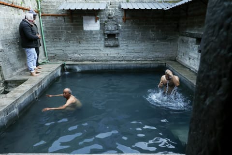 People take a dip in the Vashisht temple's hot spring