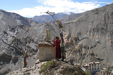 A Buddhist Monk putting up prayer flags