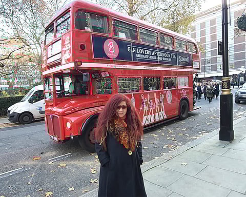 Husain posing in front of London's double-decker bus