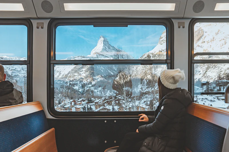 young woman traveling looking out the window enjoying in Swiss Alps with the Matterhorn in winter background