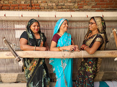 A group of women posing in front of their handloom