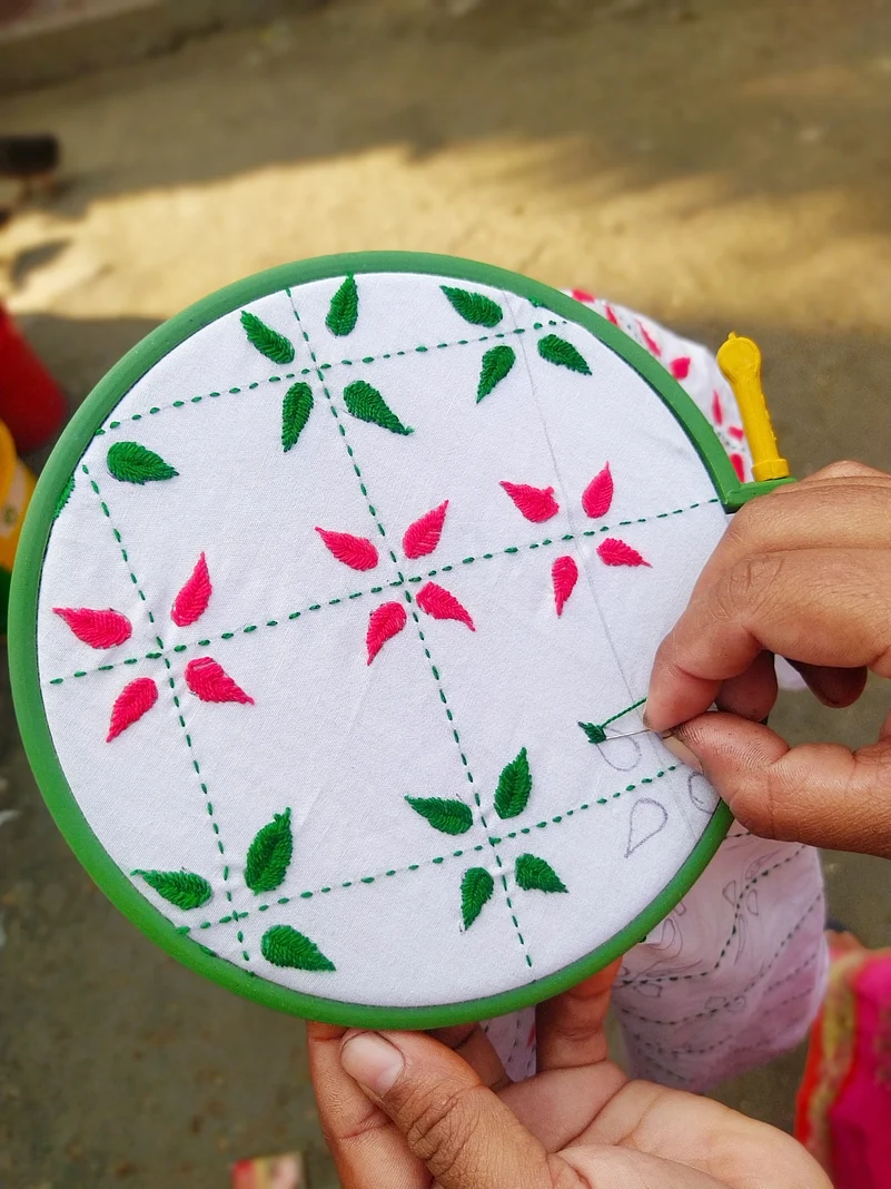 A woman making design on a Nakshi Kantha