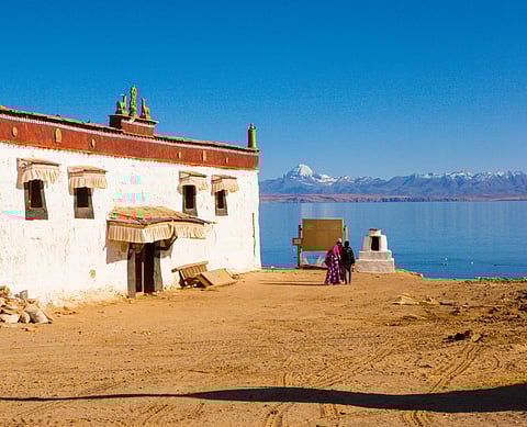 A monastery, with the Kangrinboqe Peak and Lake Manasarovar in the background