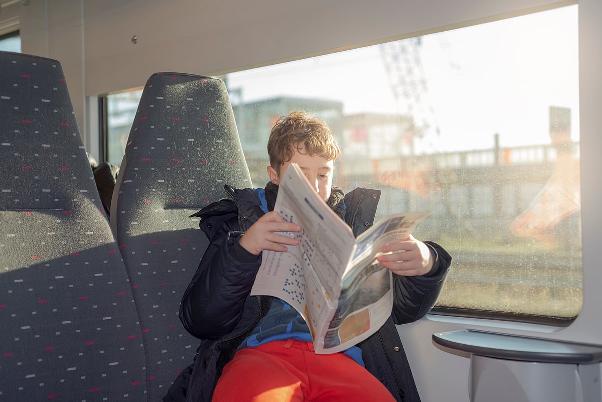 Boy reading a newspaper on a train