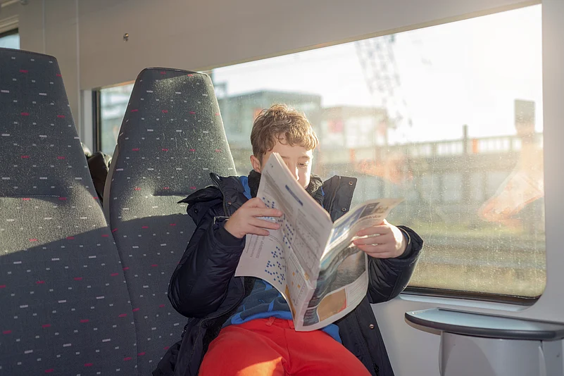 Boy reading a newspaper on a train