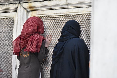 Women stand at the dargha whispering their prayers through the jaali